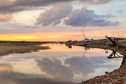 Low tide channel at Morston Quay reflecting the sky with boats resting nearby