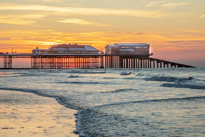 Cromer Pier illuminated at night with reflections on the sea