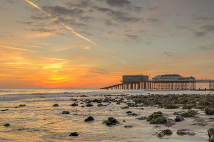 Cromer Pier at low tide with rocky shoreline and glowing sky Norfolk