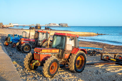 Traditional crab fishing tractors on Cromer beach with pier in background