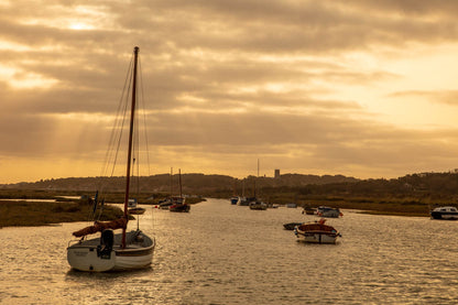 Golden light over Morston Quay creek with boats on calm water