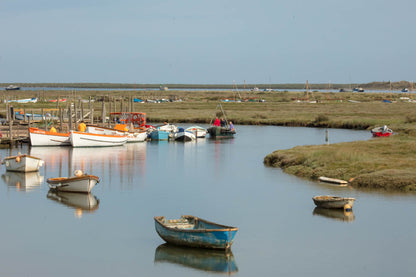 Moored boats at a bend in Morston creek with salt marsh landscape