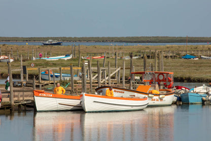 Boats alongside the jetty at Morston Quay with people preparing for a trip