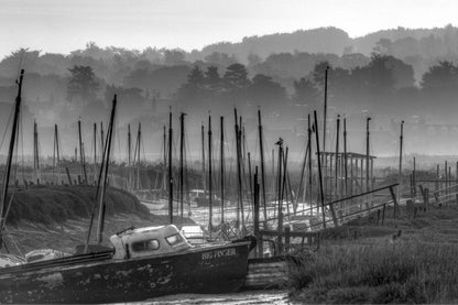 Black and white misty harbour at Morston Quay with boats and masts