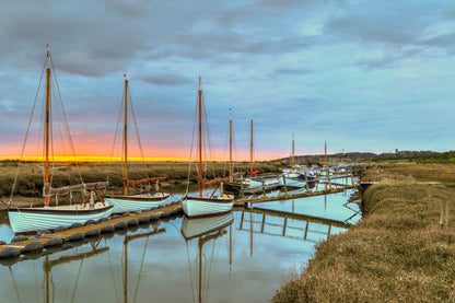Dawn light over Morston Quay harbour with boats and still water