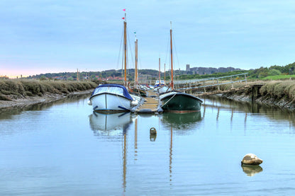 Two boats reflected in calm water at Morston Quay harbour
