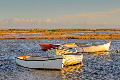 Morston Quay harbour scene with boats on the tidal creek and wide marsh sky